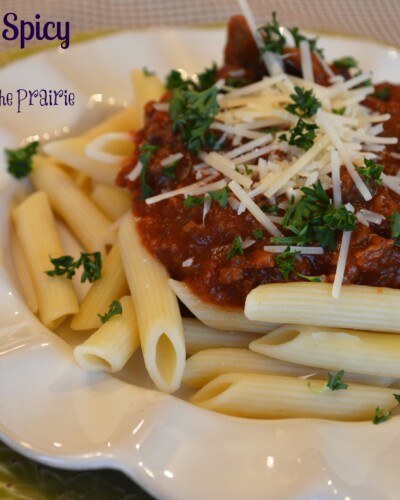 a white plate with penne noodles topped with beef in a tomato and cube steak sauce