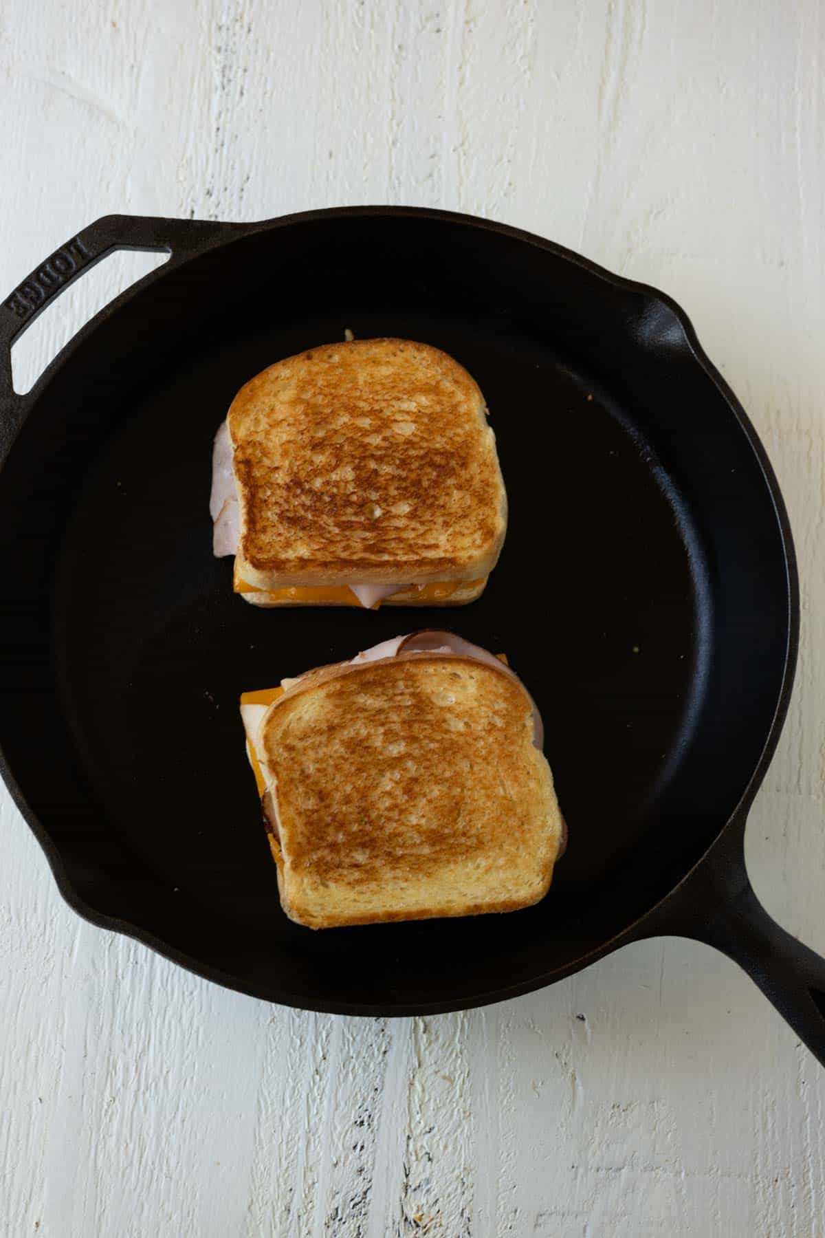 Golden brown grilled cheese sandwiches in a cast iron skillet.