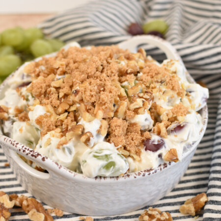 grape salad in a white dish topped with brown sugar and chopped walnuts