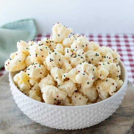 Almond bark puffcorn with Christmas sprinkles in a white bowl.