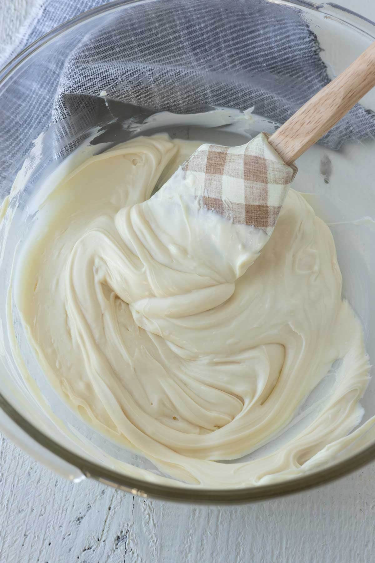Melted white chocolate in a glass mixing bowl.