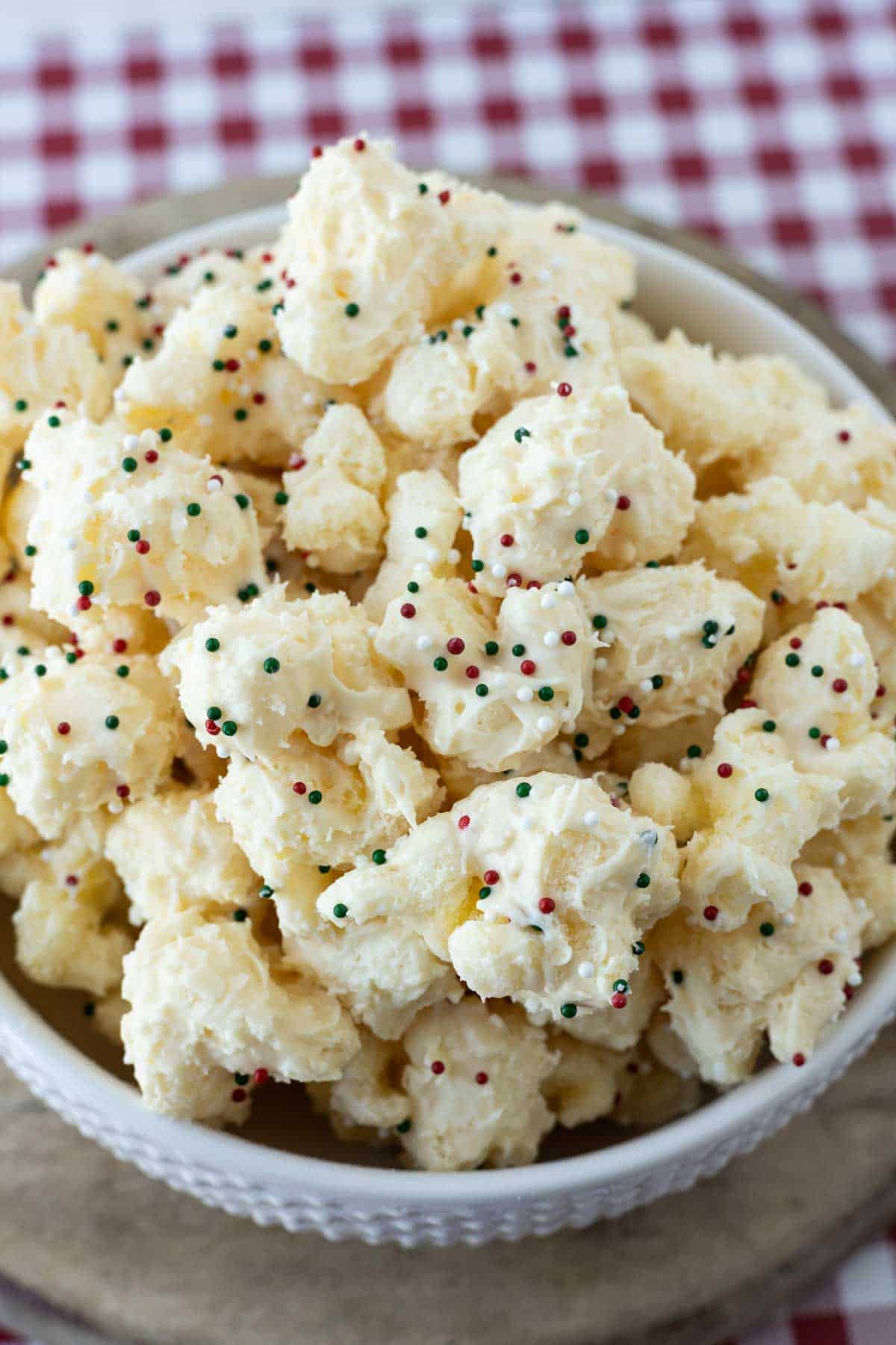 A white bowl with white chocolate puff corn and Christmas sprinkles.