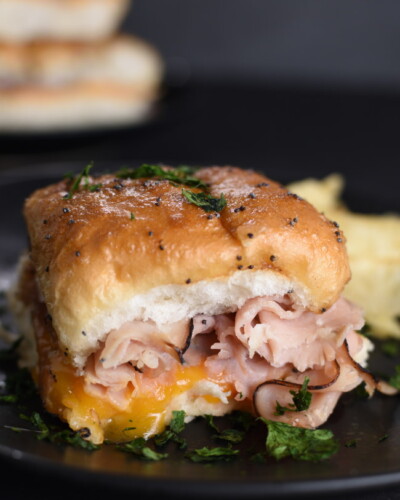 baked ham and cheese slider on a black plate