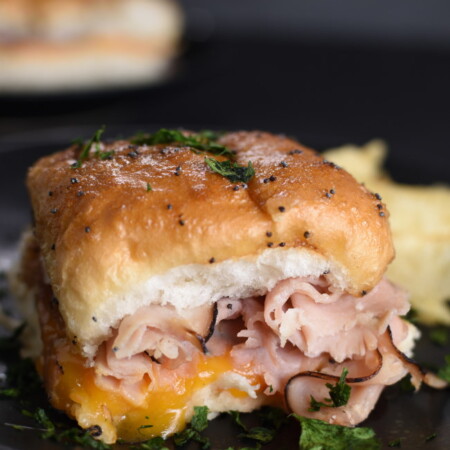 baked ham and cheese slider on a black plate