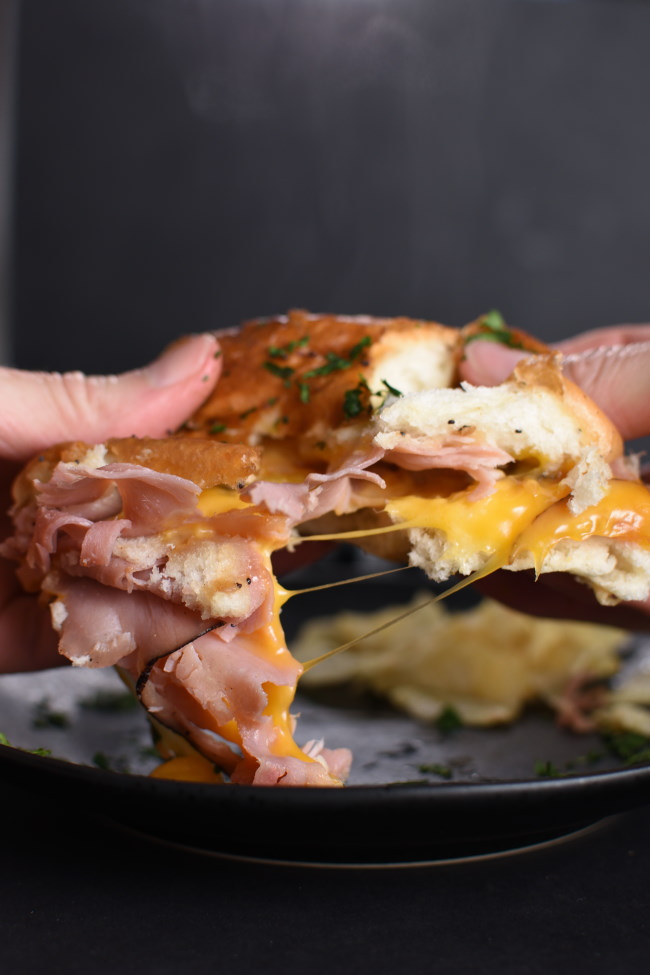 a hot ham and cheese slider being pulled apart