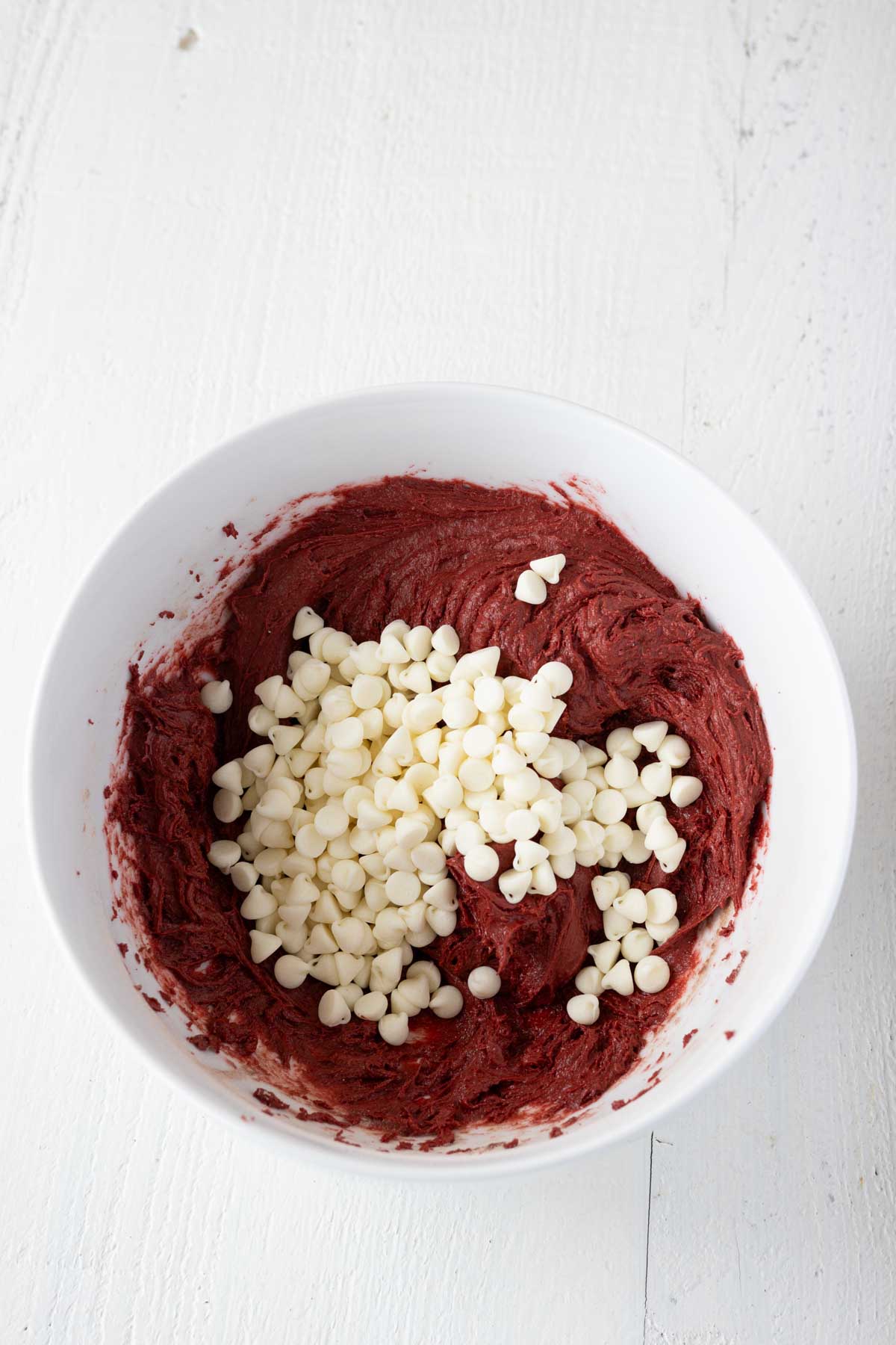 Red velvet cake mix cookie dough with white chocolate chips in a mixing bowl.