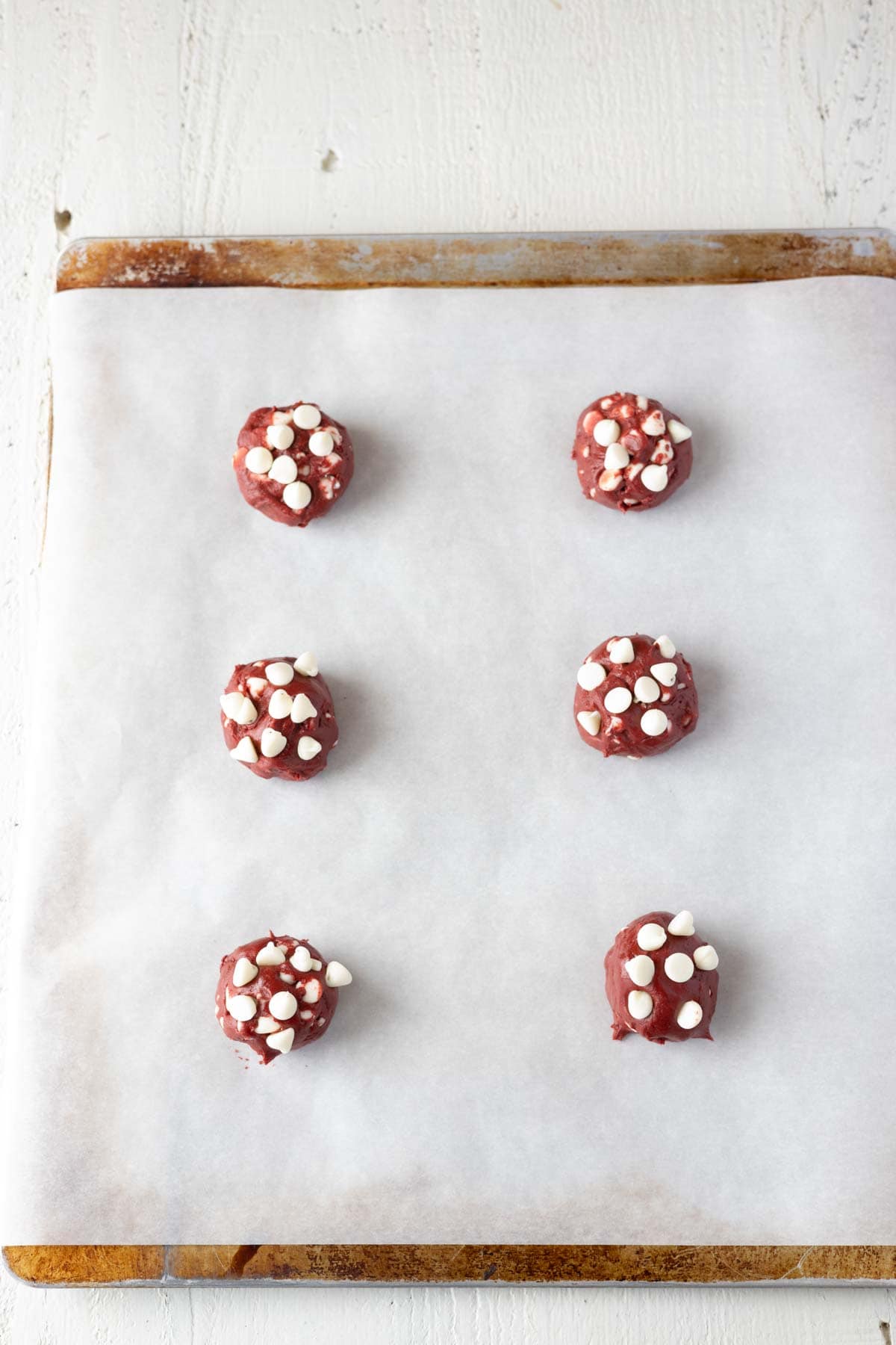 White chocolate chip red velvet cookies on baking sheet.