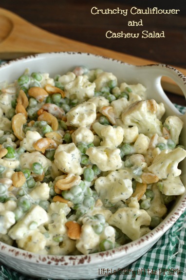 A white dish with cauliflower, cashews, and green peas tossed in a creamy dressing