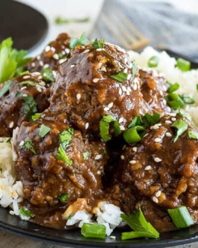 Meatballs in sweet and sour sauce with sesame seeds and herbs served over rice.