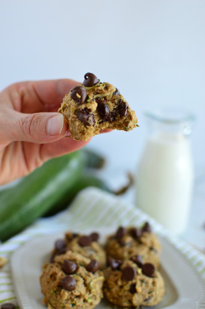 a hand holding a thick zucchini cookie with a bite taken out of it