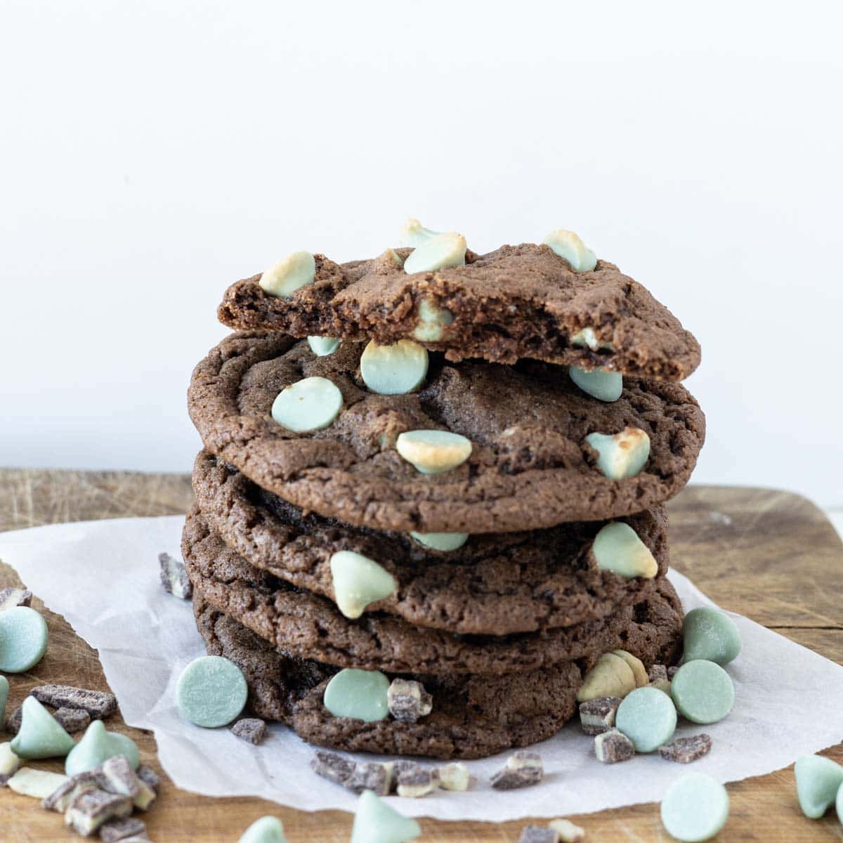 A stack of mint chip chocolate cookies with a bite taken out of the top cookie.