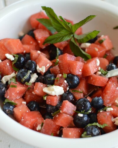 cubed watermelon, blueberries, and crumbled feta cheese in a white bowl with a spoon