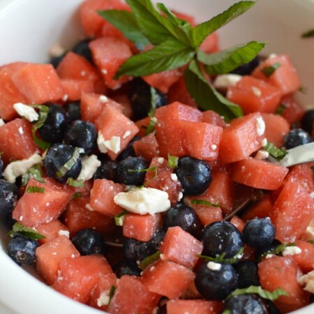 cubed watermelon, blueberries, and crumbled feta cheese in a white bowl with a spoon
