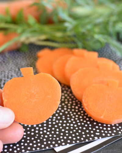 carrots carved to look like pumpkins on a black piece of paper