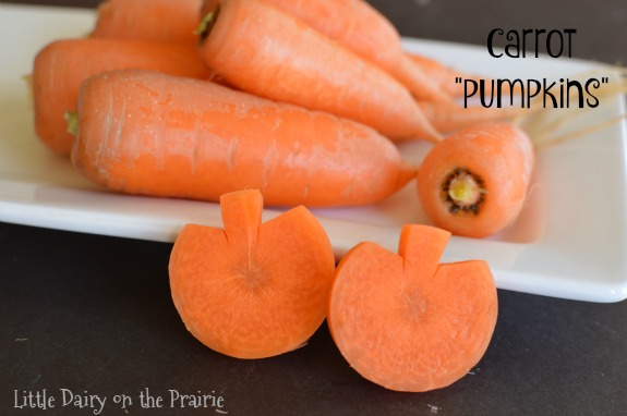 whole carrots on a white plate with carrot slices shaped like pumpkins