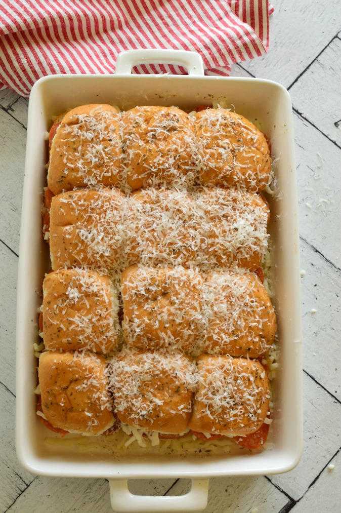 Sliders in a white baking dish with parmesan cheese on top