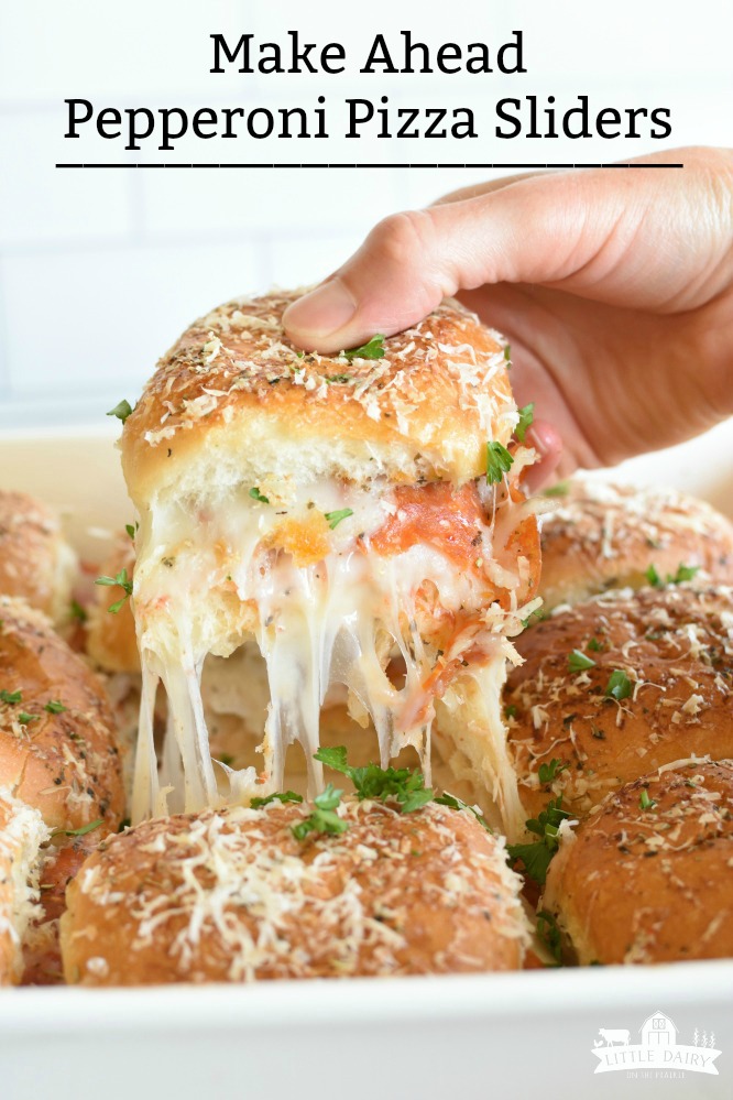 a hand pulling a pizza slider out a pan with gooey cheese
