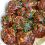 a white dish with meatballs tossed in barbecue sauce