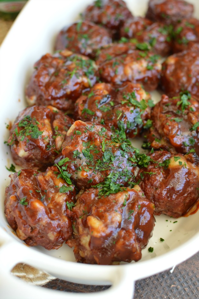 a white dish with meatballs tossed in barbecue sauce