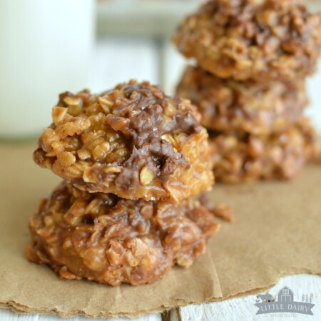two no bake salted caramel cookies stacked on a paper with a jug of milk