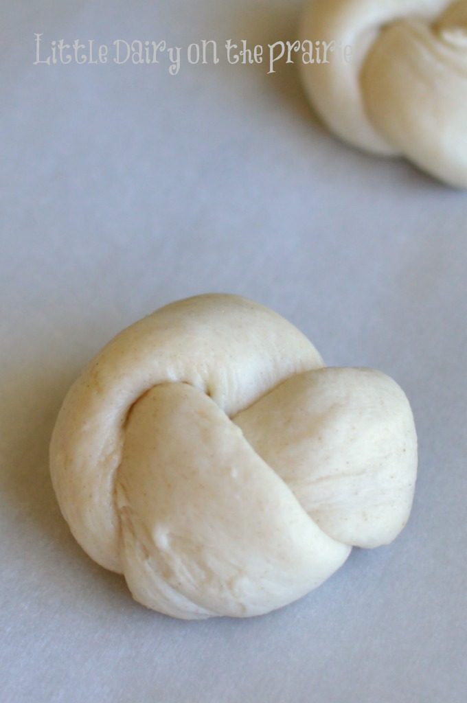 raw biscuit dough shaped into bread knots on a baking sheet