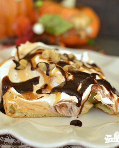 a square of dessert with a puff pastry crust, pumpkin cream layer, and topped with whipped topping, drizzled with caramel and hot fudge topping