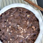 a white round baking dish with hot chocolate pudding cake, topped with minin marshmallows
