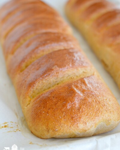a loaf of golden brown baked french bread with slices in the top