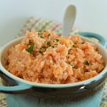 a blue pot filled with spanish rice topped with chopped cilantro