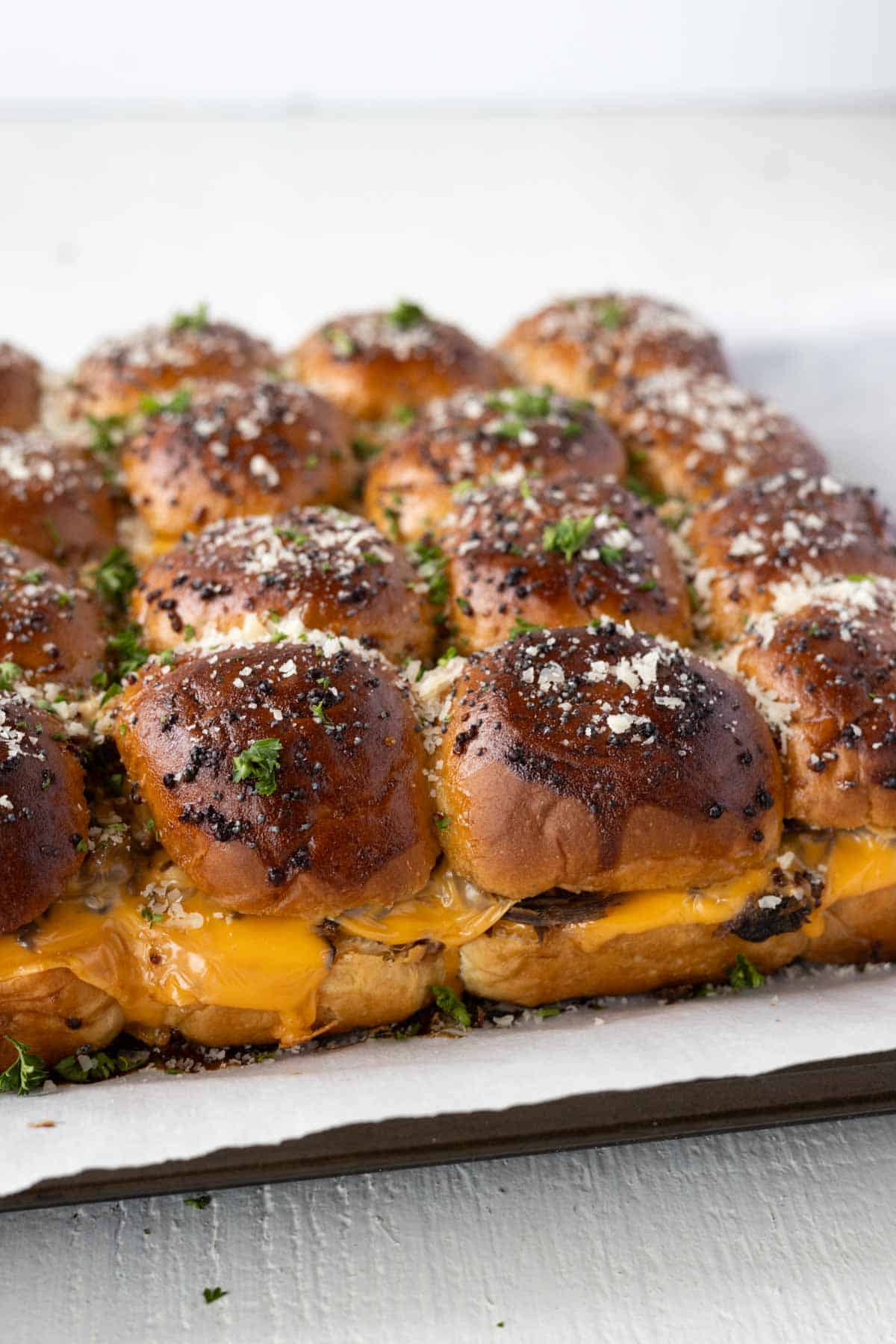 Baked cheddar and roast beef sliders on a baking sheet.