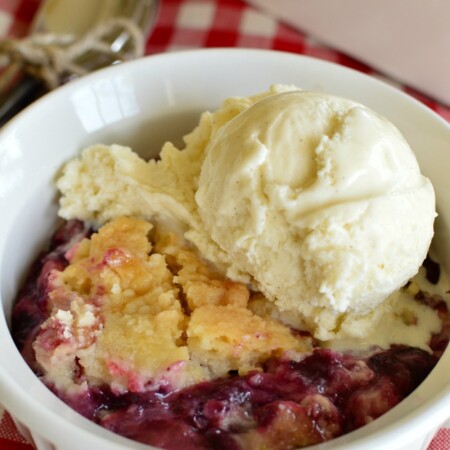 a bowl with rhubarb fillilng topped with cobbler crust and vanilla ice cream
