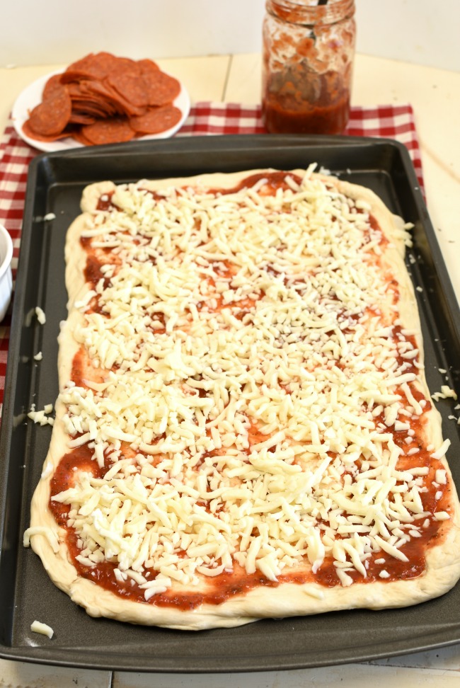 Pizza crust with marinara and grated mozzarella cheese.