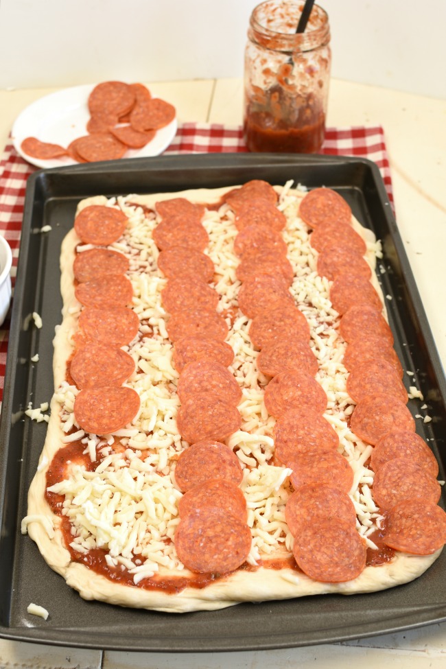 Flag pizza with stripes made with pepperoni slices.