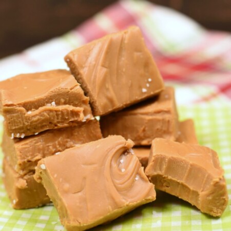 a stack of caramel candy squares on a green and white paper