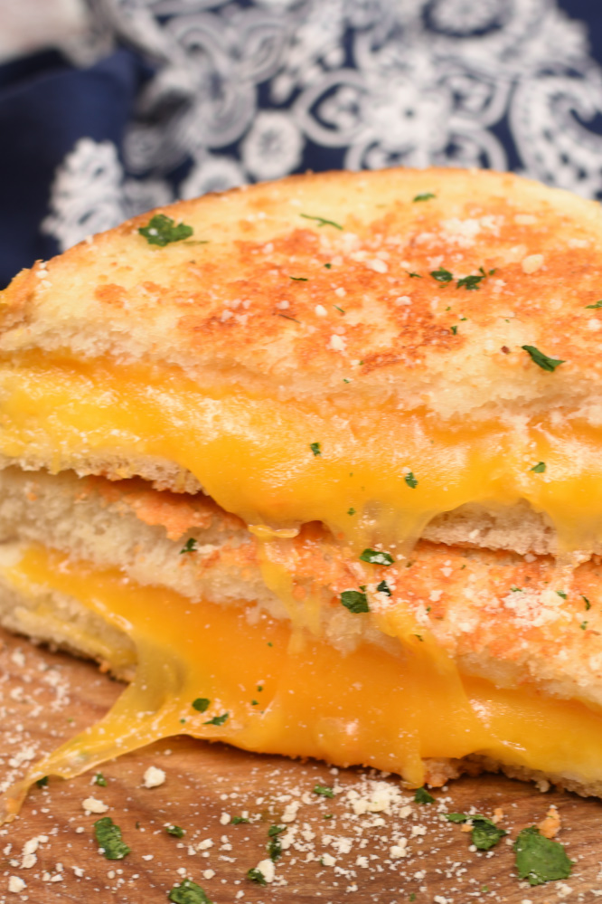 The only thing better than a toasty grilled cheese sandwich filled with gooey melted cheese on the inside, is a Parmesan Crusted Grilled Cheese Sandwich with the most incredible crispy garlic Parmesan crust on the outside! Today I’m beyond excited to share my Parmesan Grilled Cheese Sandwich with you guys! I’ve always been a HUGE lover of grilled cheese sandwiches because who could ever resist ooey gooey cheese nestled between golden brown buttery bread? Not me! Let me tell you though, the crust on my Parmesan Grilled Cheese Sandwich is so stinkin’ divine! It’s so good your going to sink back into your chair, close your eyes and fall in love! Something magical happens when you combine the soft melted cheese on the inside with that crispy, golden brown, buttery and cheesy crust on the outside! Well, by now you know that I married a dairy farmer and have lived on this stinky ol’ farm for almost twenty years! I can’t believe it’s been that long since I agreed to live here with all these cows, flies, crazy hours, and pretty much be joined at the hip with this farm! After I met Justin and he told me he was a dairy farmer I think my heart sunk a little! He was a really great guy but I just didn’t want to be married to a filthy dirty, no days off, muck boot wearing dairyman! Right after I decided my heart didn’t need to be sunken I told him that I’d actually been supporting him for many, many years! I was convinced I was single handedly supporting the entire dairy industry with my love of cheese! I can pound more cheese in a month than most people can pound in a whole year. Surely Justin was getting his a portion of my hard earned money I spend on cheese! I’m seriously an addict. After I’ve been on vacation for a few days I start to really crave salty cheese! I add it to every single meal I make; pasta, scrambled eggs, cheese burgers, salads, mashed potatoes, and even pancakes (don’t knock it till you try it, it’s good)! I’ll take cheese any way I can get it! But I have to admit that ultra comforting Parmesan Crusted Grilled Cheese Sandwiches will always be at the top of my list of favorite meals! It has not one, but two or more kinds of cheese and you can’t beat that! Parmesan Grilled Cheese Sandwiches are still the same old super simple to prepare sandwich you fell in love with as a kid with a fun little twist! Tips for making Parmesan Crusted Grilled Cheese Sandwiches Use soft butter Spread the butter one more time after you add parmesan cheese just to help everything to stick. Grill sandwich over medium heat so the bread doesn’t get browned before the cheese melts. Serve with jam...trust me it’s so flipping tasty! How to customize your Parmesan Crusted Grilled Cheese Sandwich Use a variety of cheeses; Swiss, cheddar, pepper jack, provolone, or a combination. Add meat; deli ham, roast beef; grilled chicken, or bacon Switch up the seasonings used in the Parmesan crust; garlic salt, Salad Supreme, Mrs. Dash’s seasonings Parmesan Crusted Grilled Cheese Sandwiches really are the ultimate comfort food! I pretty much made them twice in the last 12 hours because I happen to think they make a pretty darn good breakfast too! If you want to help me support myself and the rest of the dairy industry whip up a Parmesan Crusted Grilled Cheese Sandwich! Oh, and I’d love to know what’s your favorite kind of cheese to use in grilled cheese sandwiches and what else you pile on it! Leave me a comment and share your ideas!