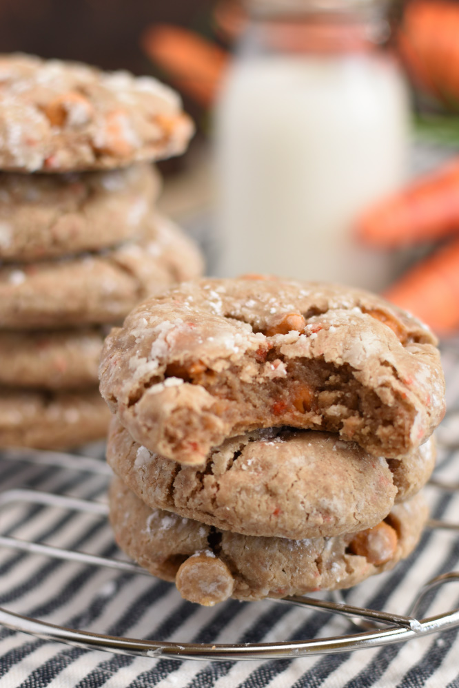 Carrot Cake Gooey Butter Cookies on a cooling rack with carrots and a glass of milk