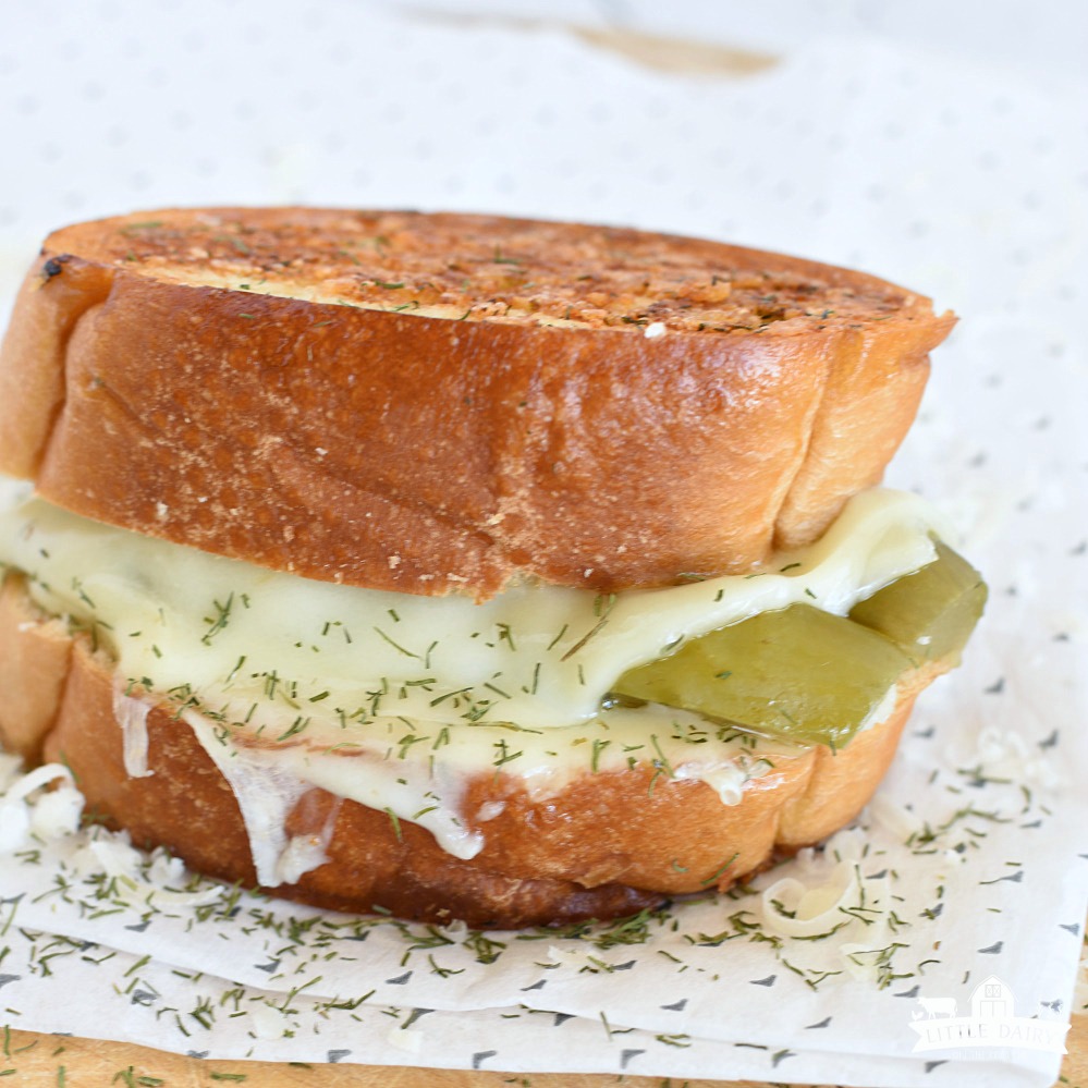 a toasted grilled cheese sandwich with melted provolone cheese and dill pickles