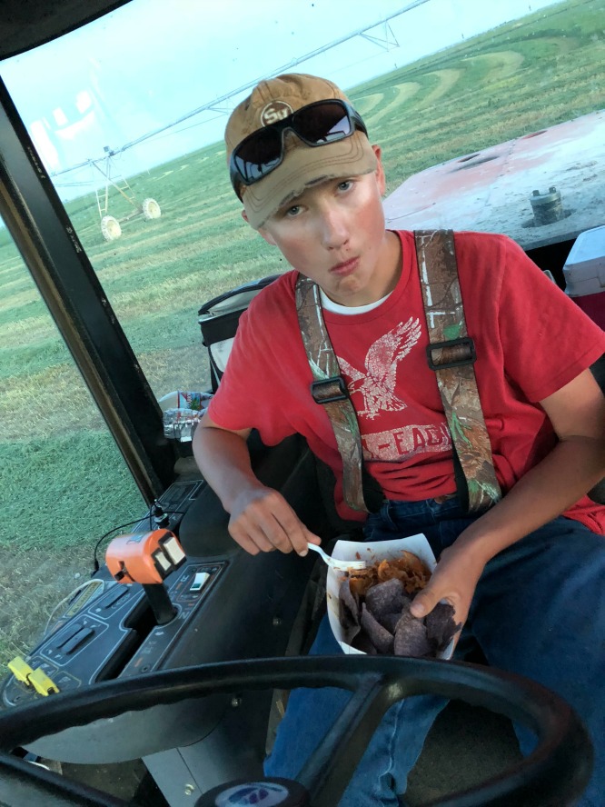 A boy in a red shirt sitting in farm equipment