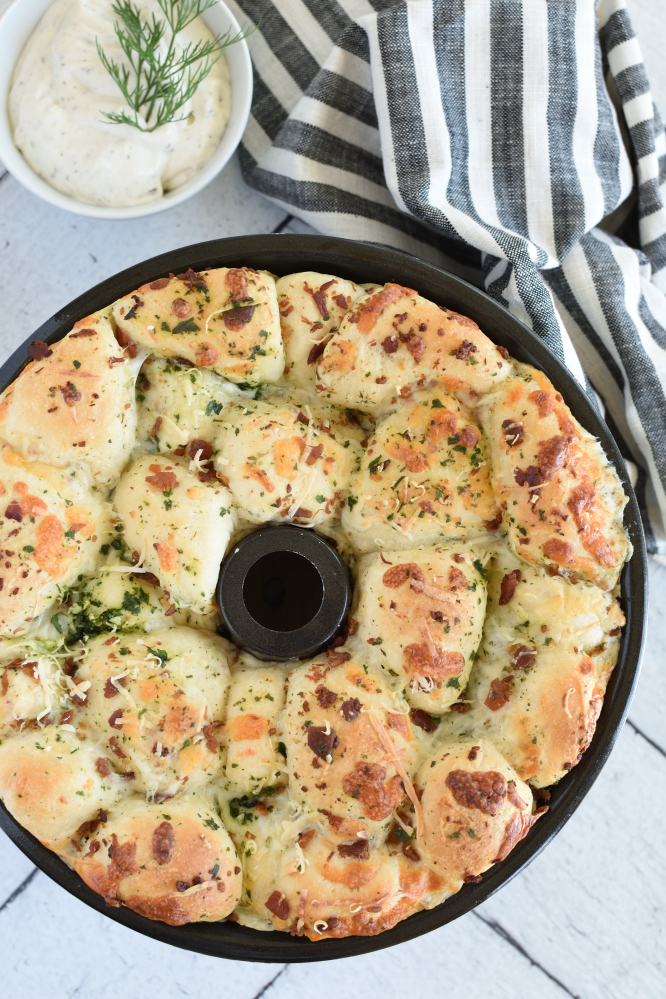 a bundt pan with baked monkey bread topped with cheese and parsely