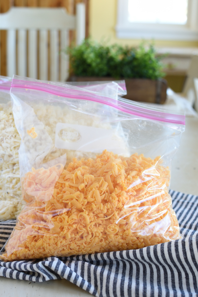 Grated cheddar cheese in a gallon sealable bag on a black and white striped napkin