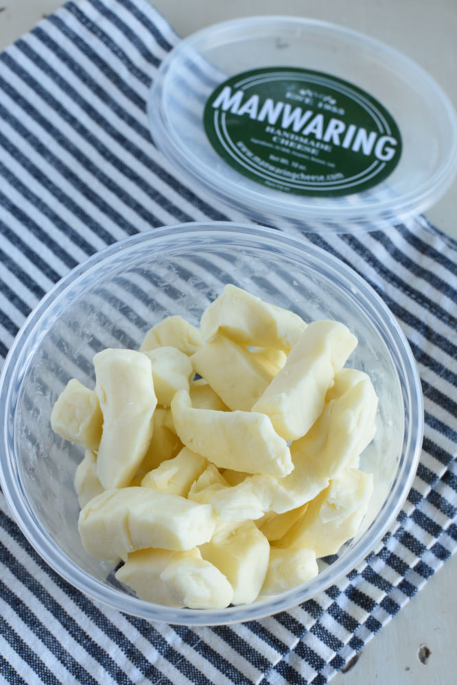 a clear container with white cheese curds on a black and white striped napking and a green lid