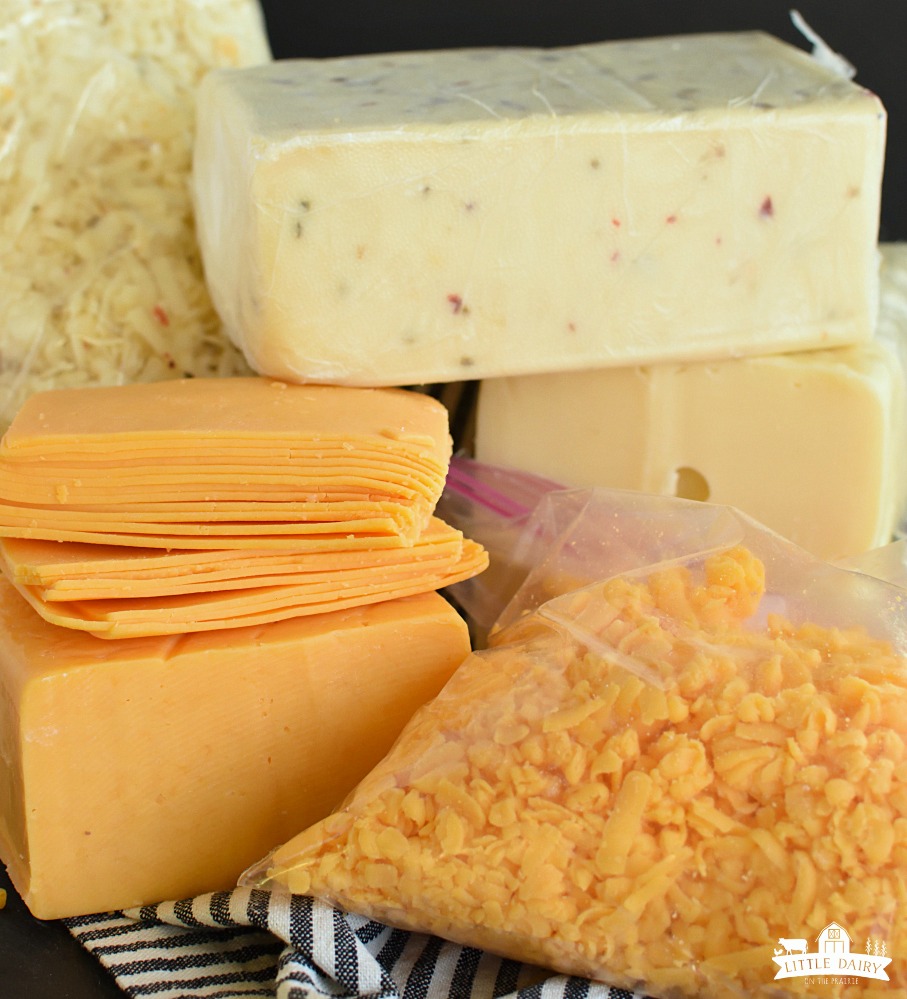 Stacks of cheese, pepperjack, swiss, cheddar, grated cheese in a bag, and sliced cheese