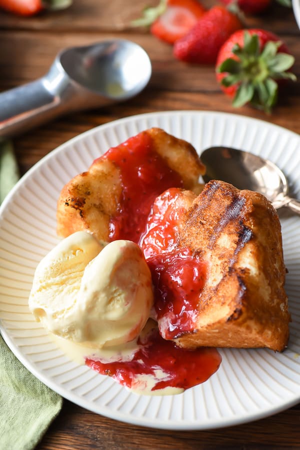 Angel Food Cake on a plate with red strawberry sauce and ice cream