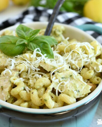 Lemon Basil Pasta Salad in a bowl with grated parmesan cheese sprinkled on top and a sprig of basil on top, with a black spoon