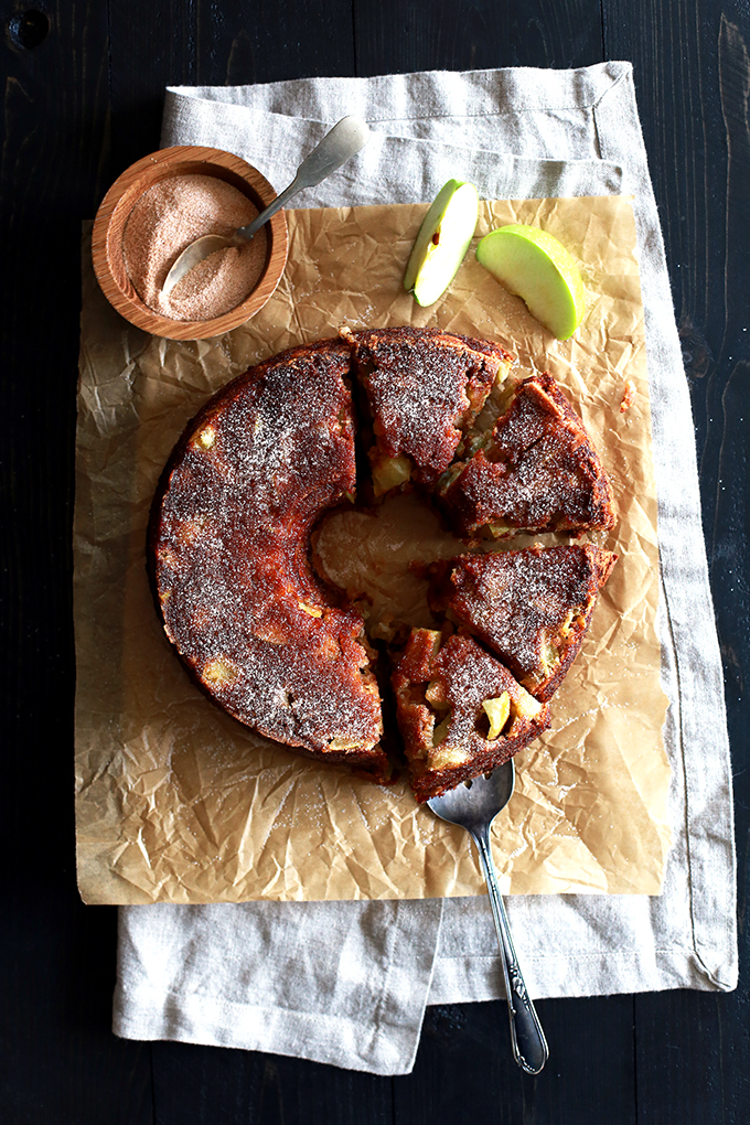 brown apple bundt cake cut in slices on a brown wrapper with sliced granny smith apples
