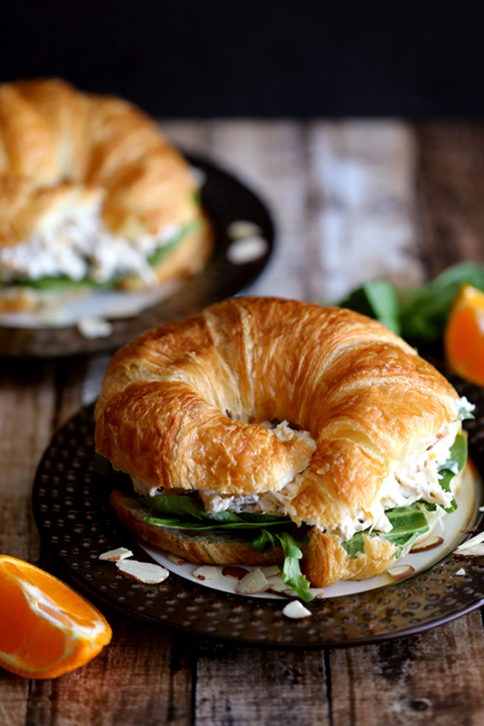 chicken salad on a croissant with green lettuce, on a black plate