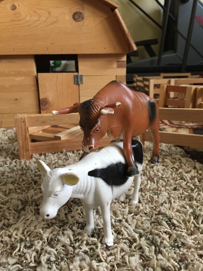 two toy cows riding each other