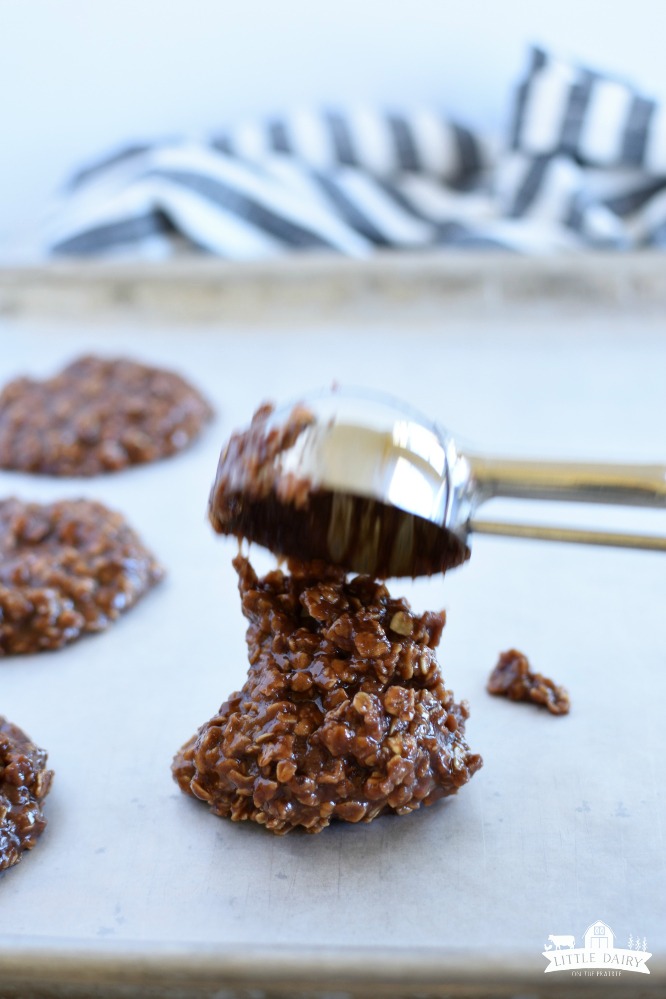 a cookie scoop dropping no bake cookies on a parchment paper lined baking sheet showing how to make no bake cookies