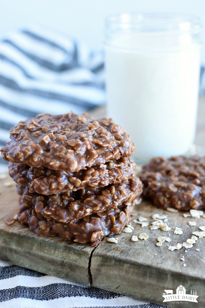 a stack of classic no bake cookies, a jar of milk, and one no bake cookie on a board with oat
