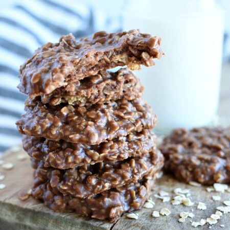 a stack of peanut butter no bake bake cookies, a jar of milk, the top cookie has a bite taken out of it